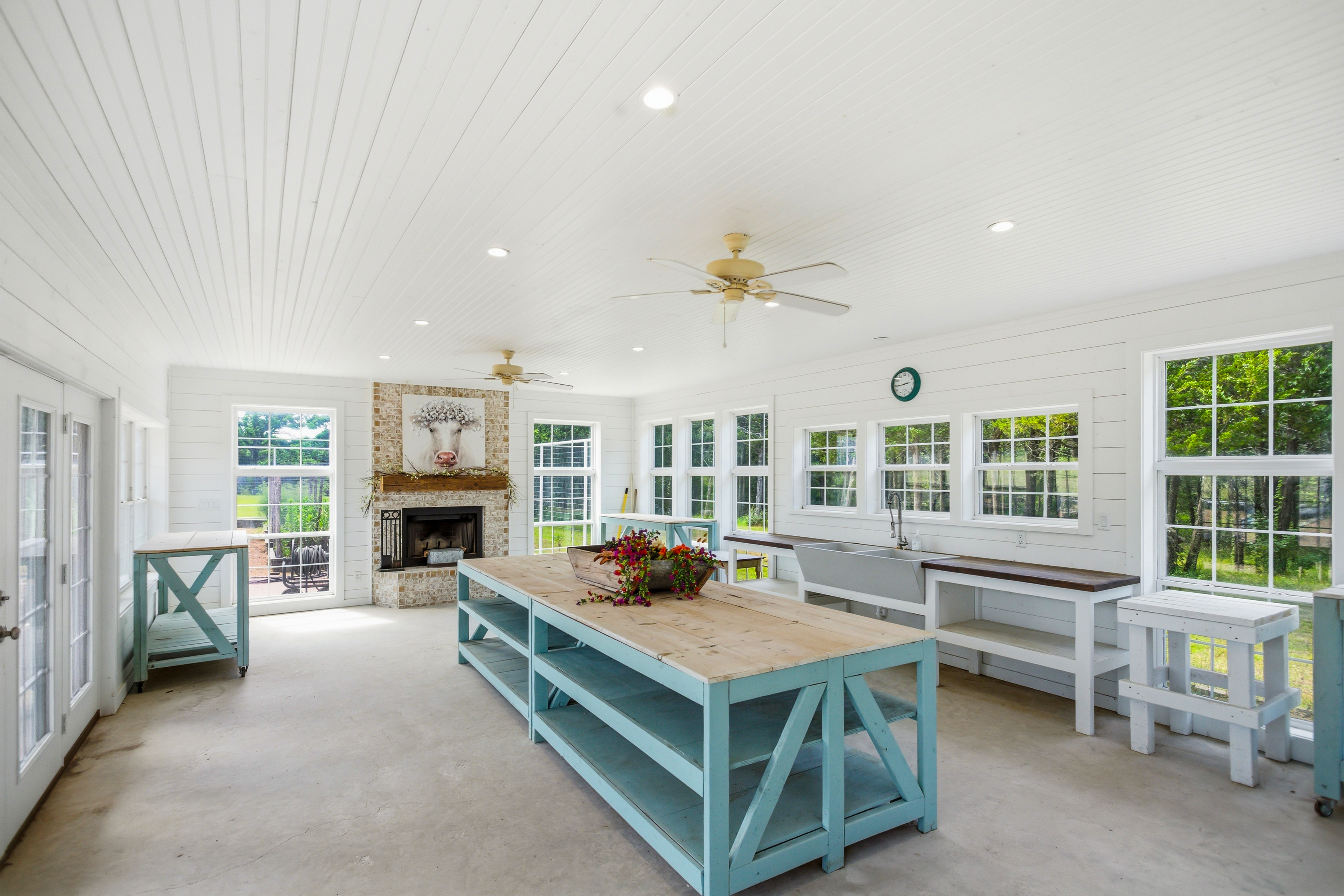 Sunroom with white shiplap walls, stone fireplace, and multiple windows