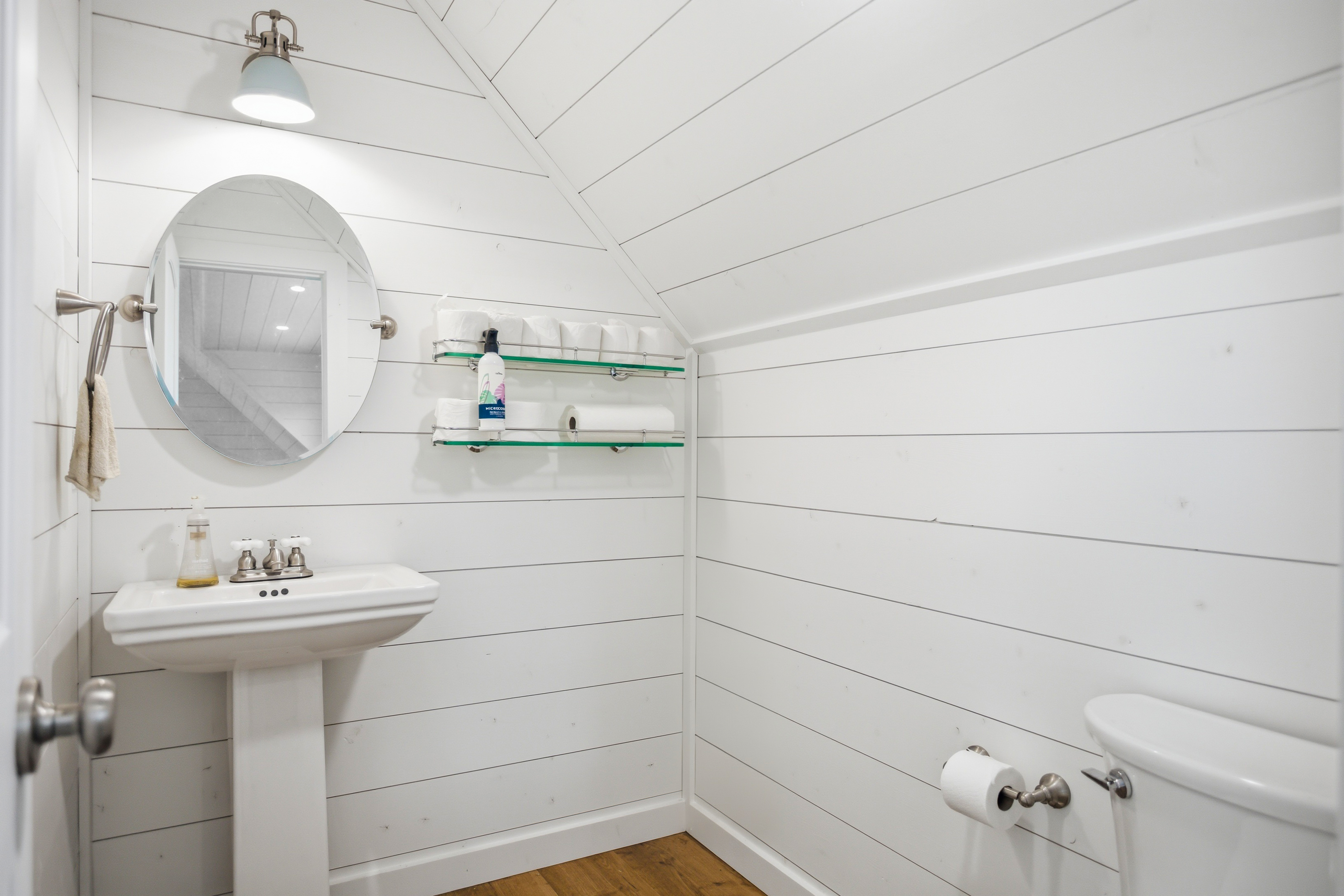Shiplap bathroom with pedestal sink and wood flooring