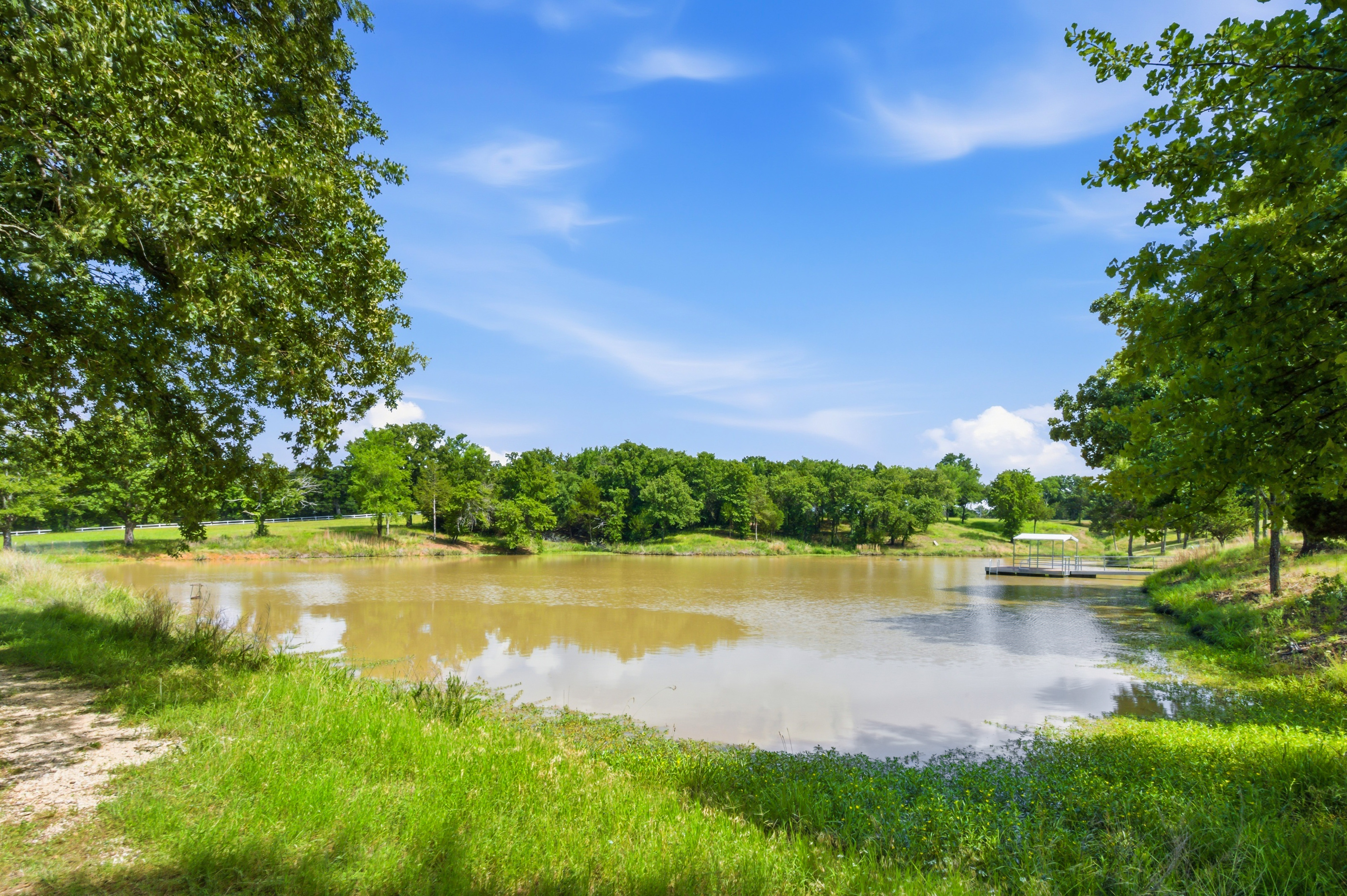 Large pond with covered dock and rolling hills backdrop