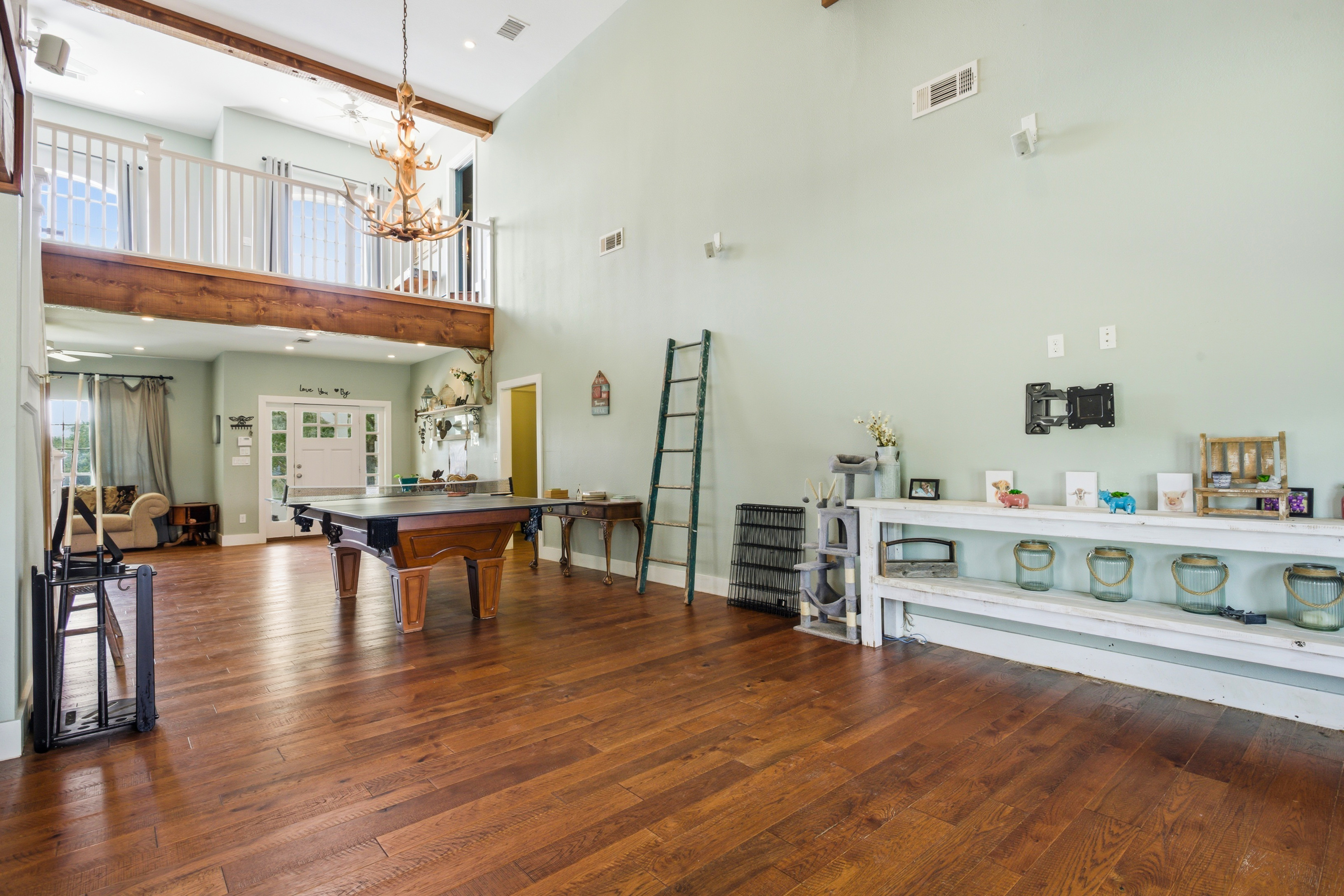 Double-height vaulted ceiling with mezzanine loft in the great room, soaring overhead with natural light flooding through upper windows