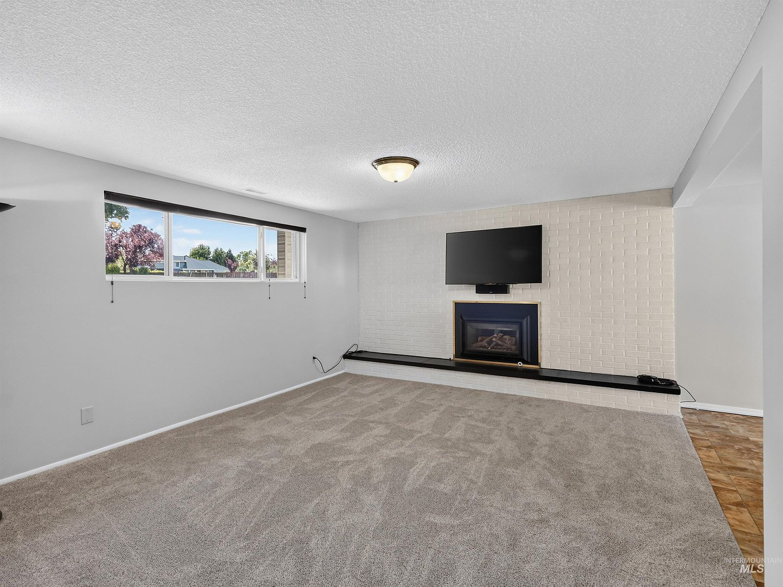 Lower-level family room with painted brick gas fireplace