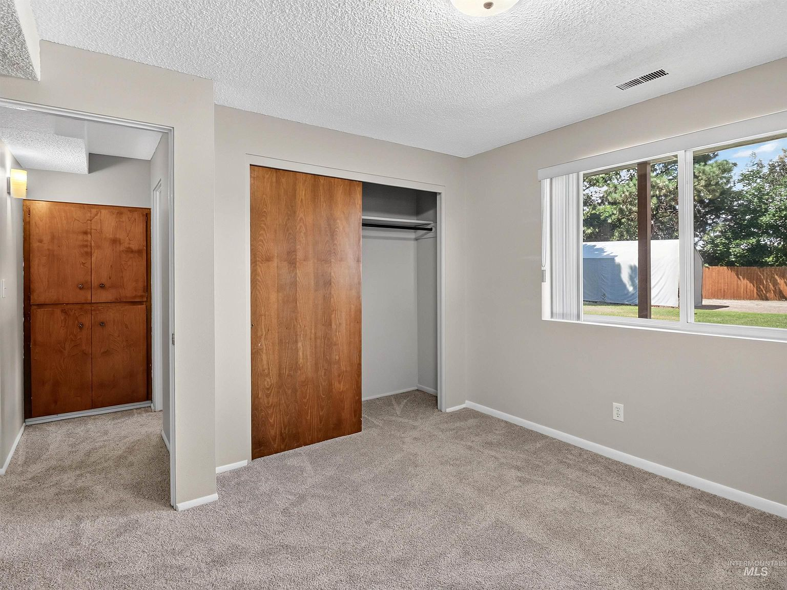 Bedroom with wood sliding closet doors and landscape window