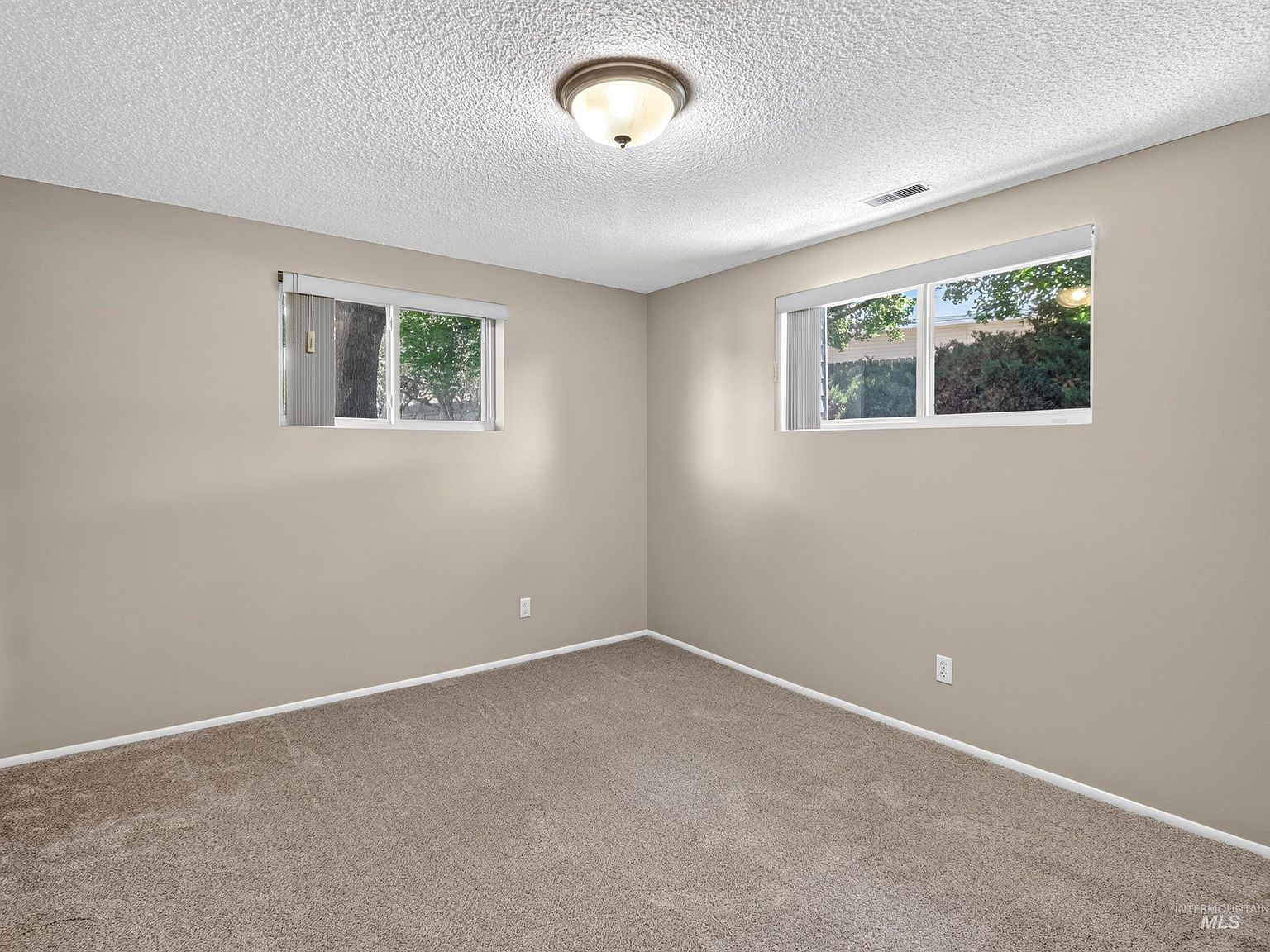 Vacant bedroom with neutral beige walls and brown carpet