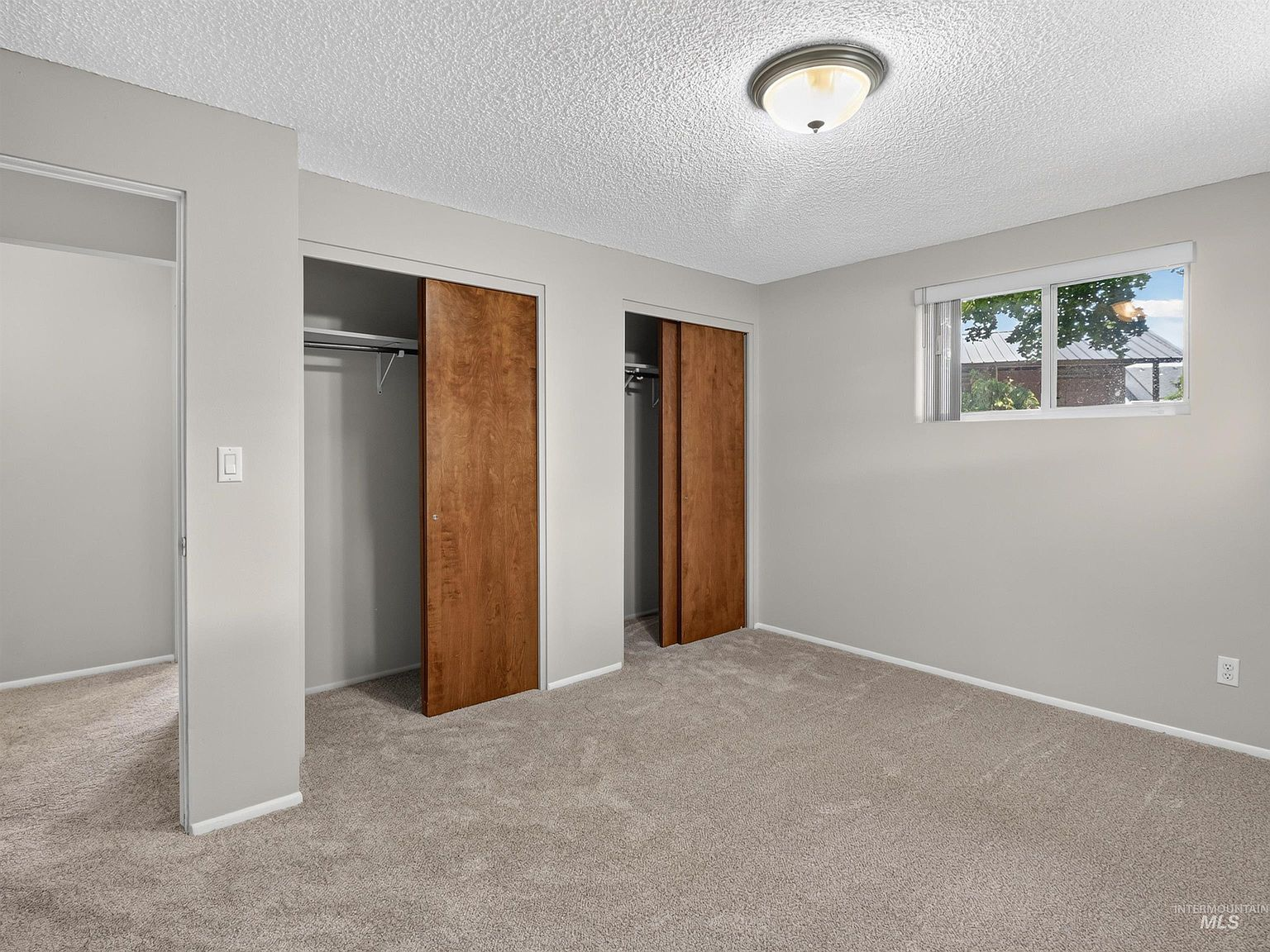 Bedroom with wood sliding closet doors and light grey walls