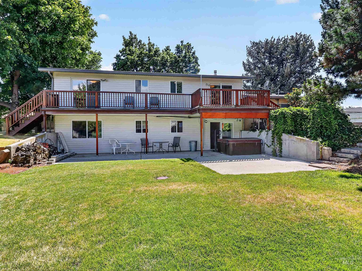 Backyard view showing two-story rear elevation with deck, patio, and hot tub