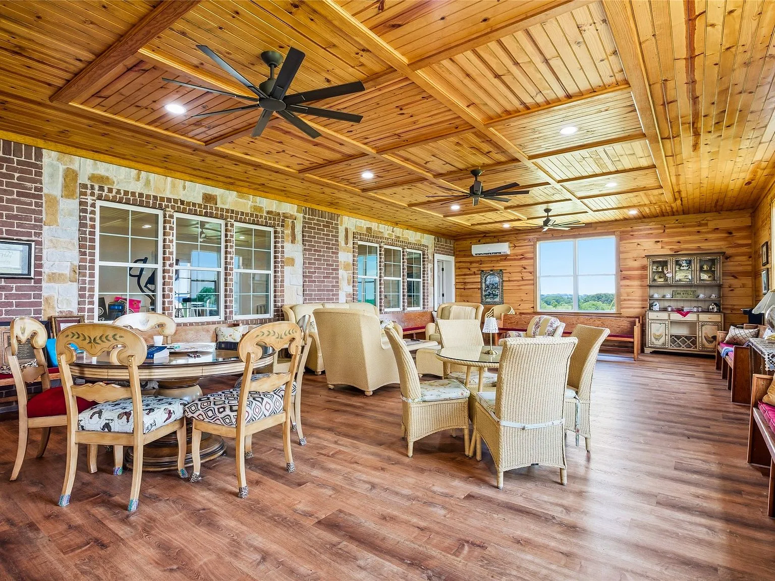 The Serenity Room with cedar coffered ceiling, stone walls, and pastoral views through expansive windows