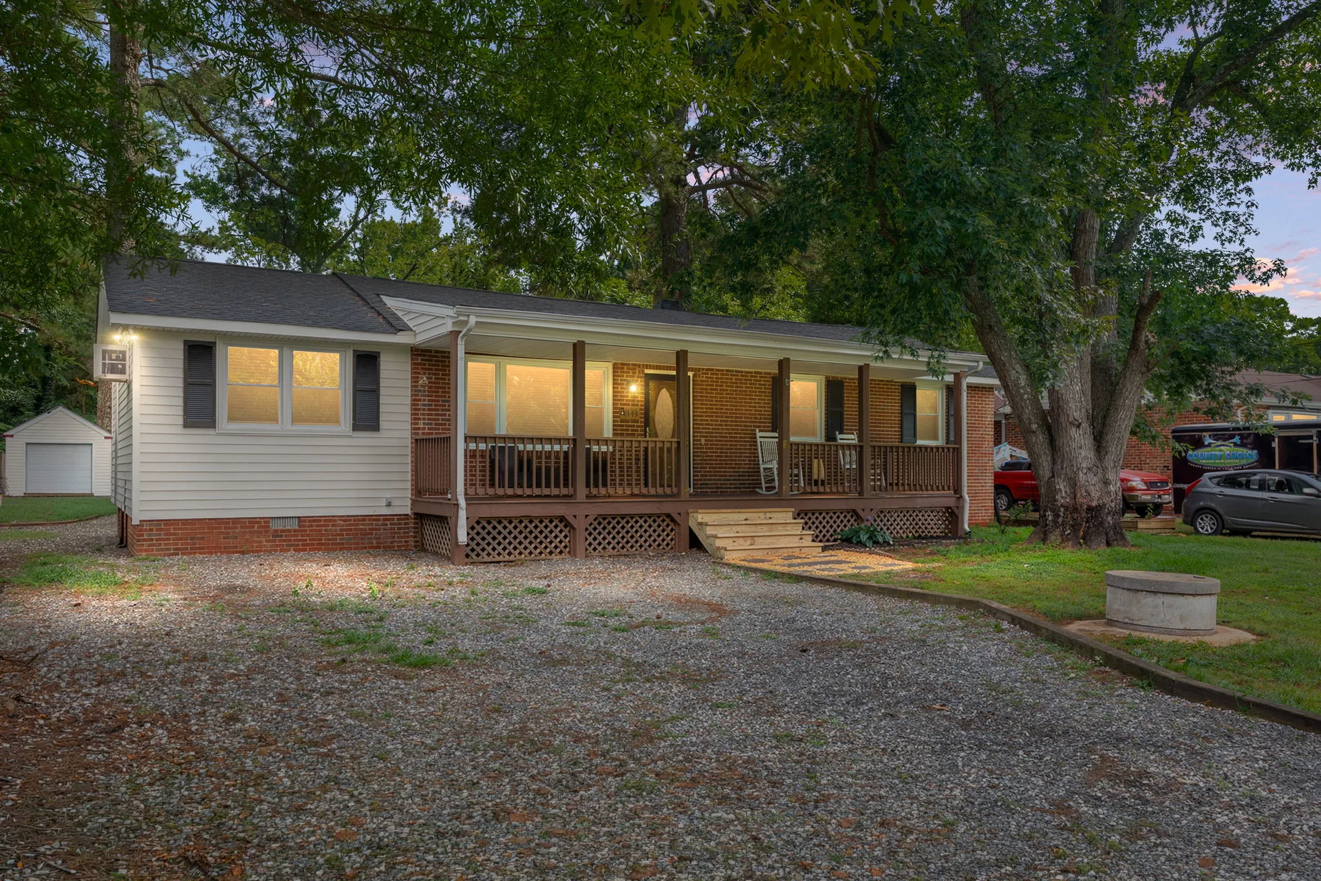 Full property view at dusk with gravel driveway and detached outbuilding