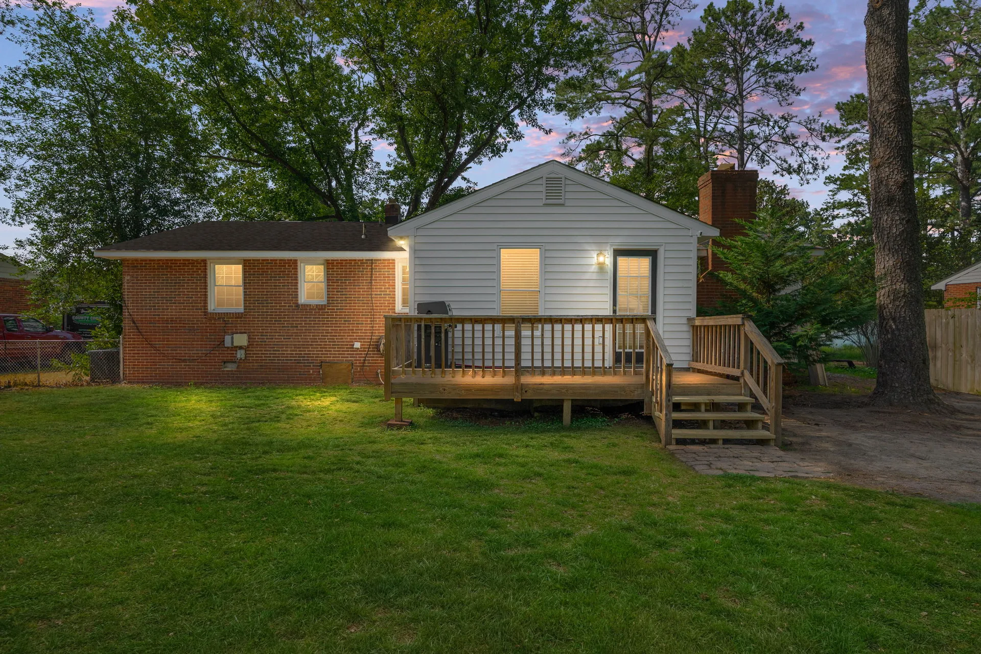 Rear facade and back deck at dusk with exterior lights
