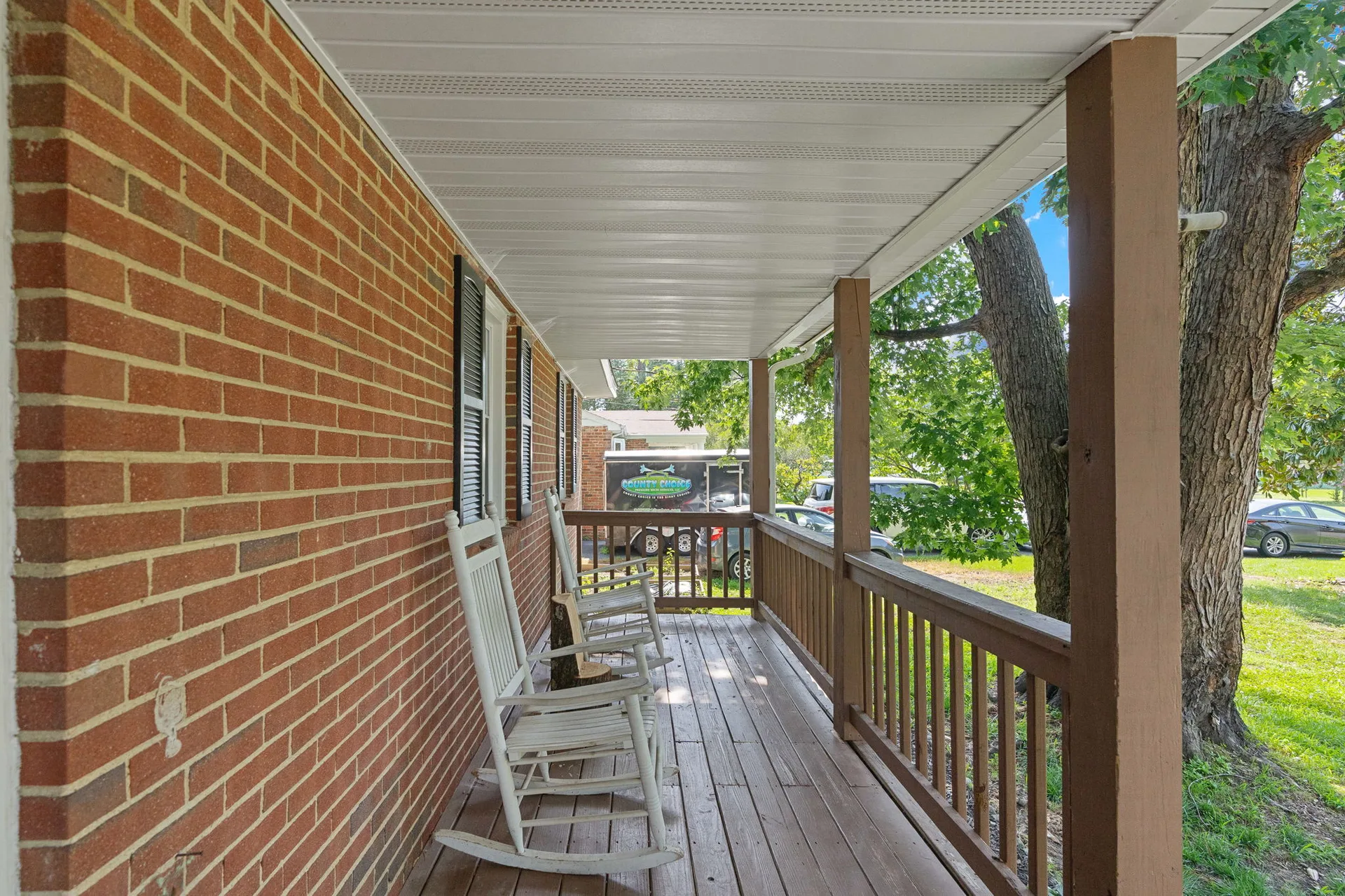 Covered front porch with wooden railings and composite decking