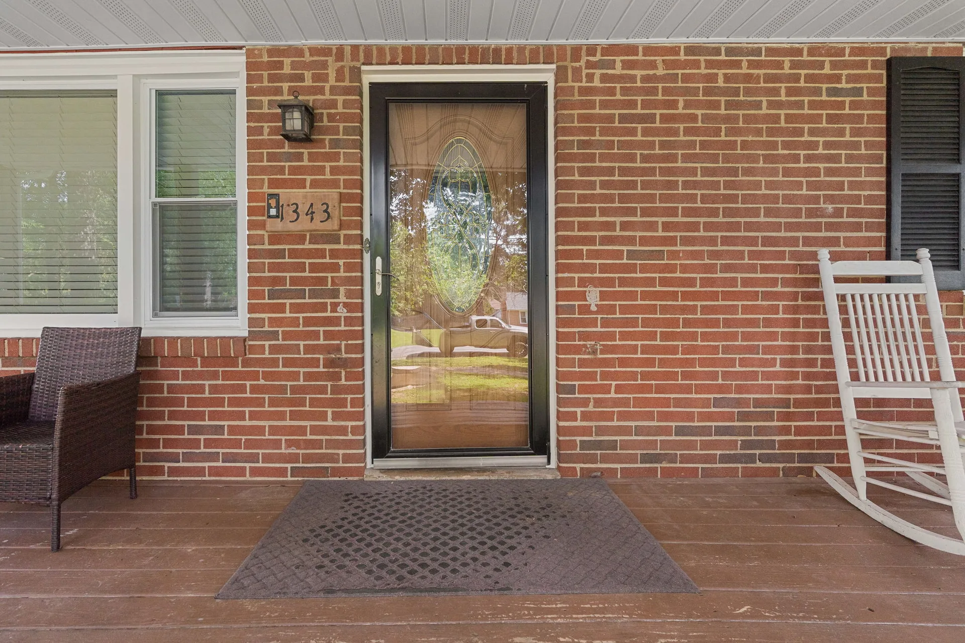 Front porch entryway with storm door and brown decking