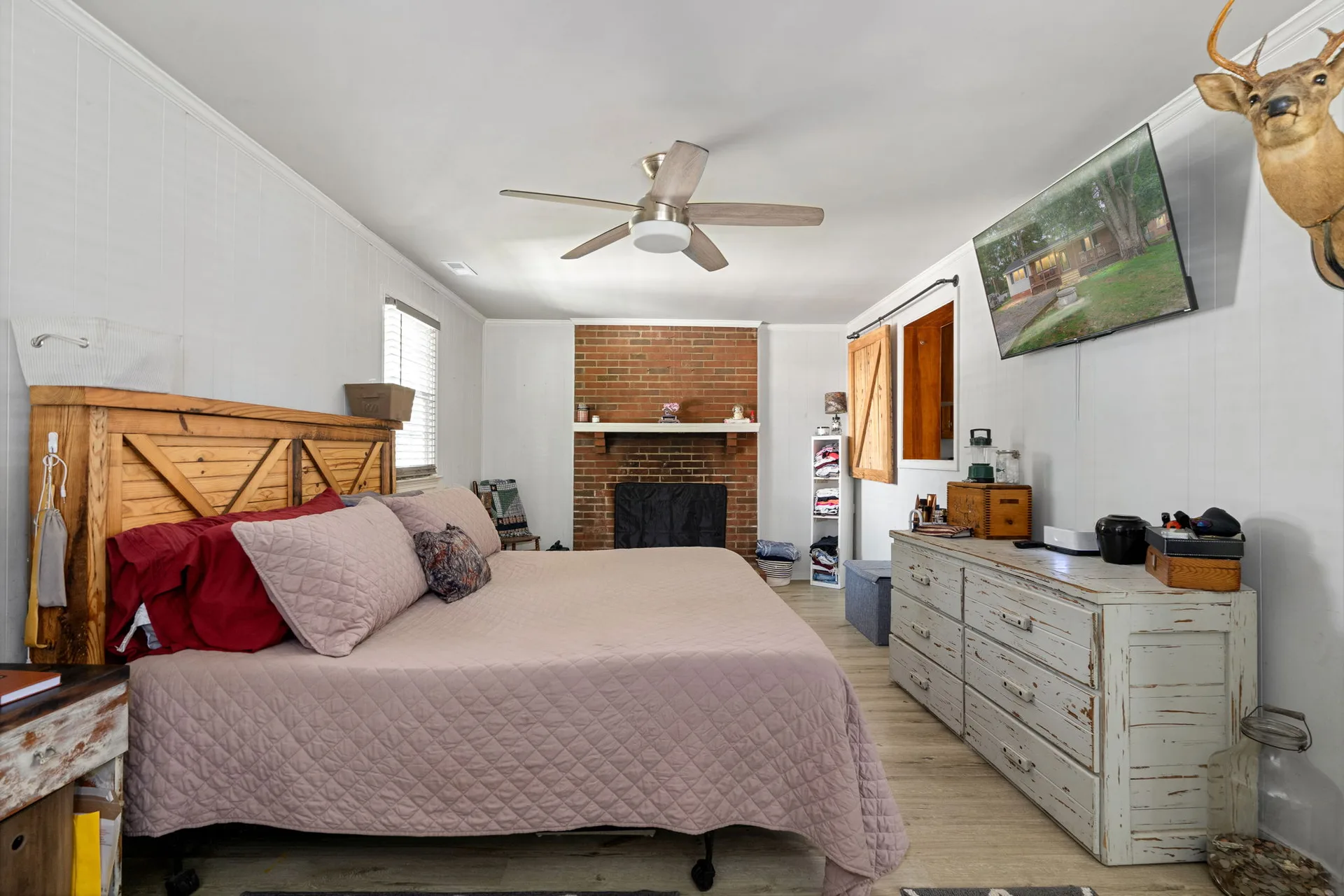 Master bedroom with brick fireplace and wood-look flooring