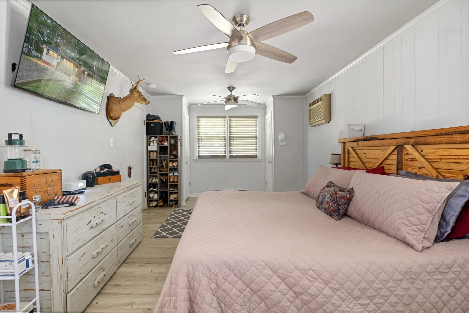 Master bedroom with mounted TV and wood-look flooring