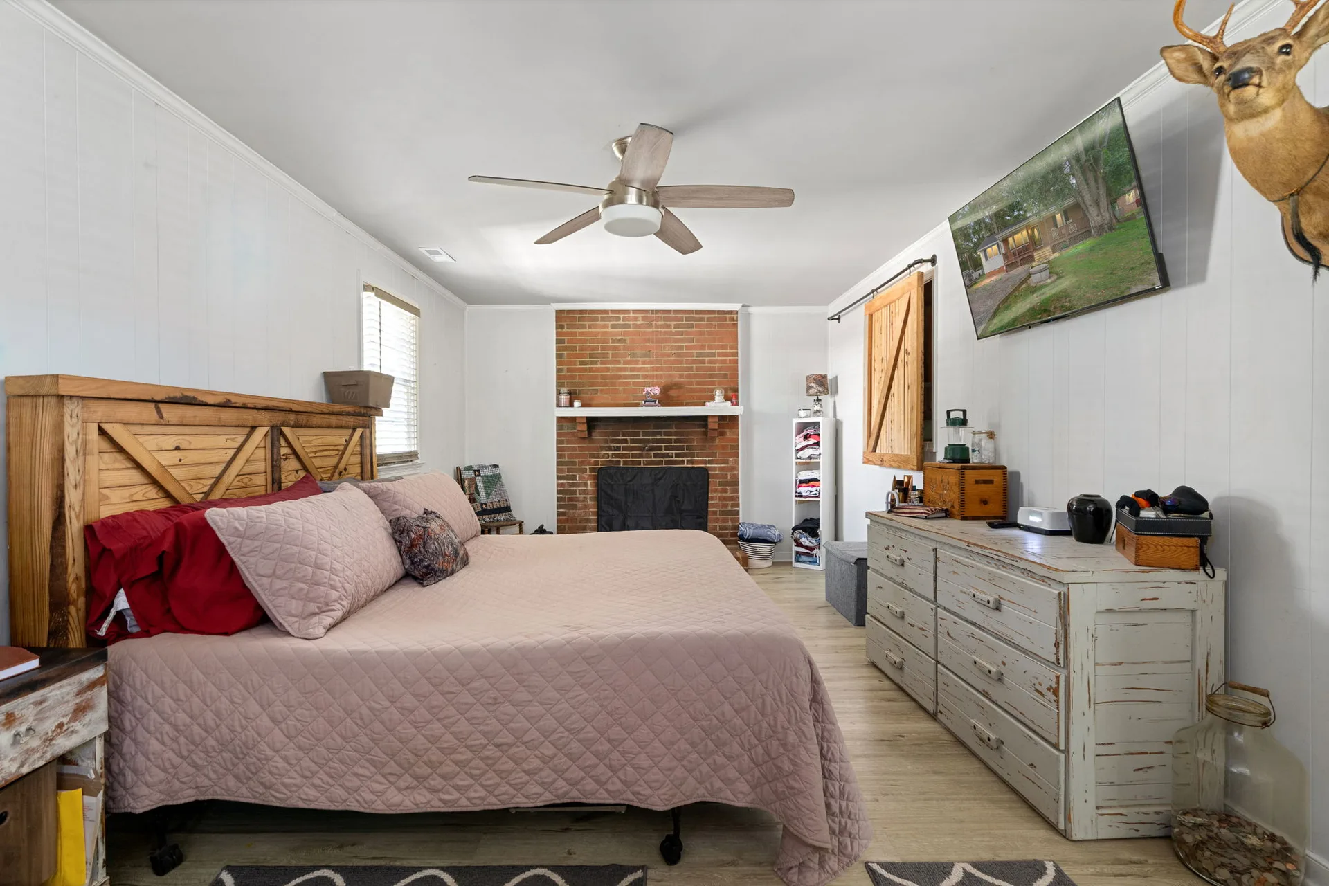 Primary bedroom with exposed brick fireplace and sliding barn door
