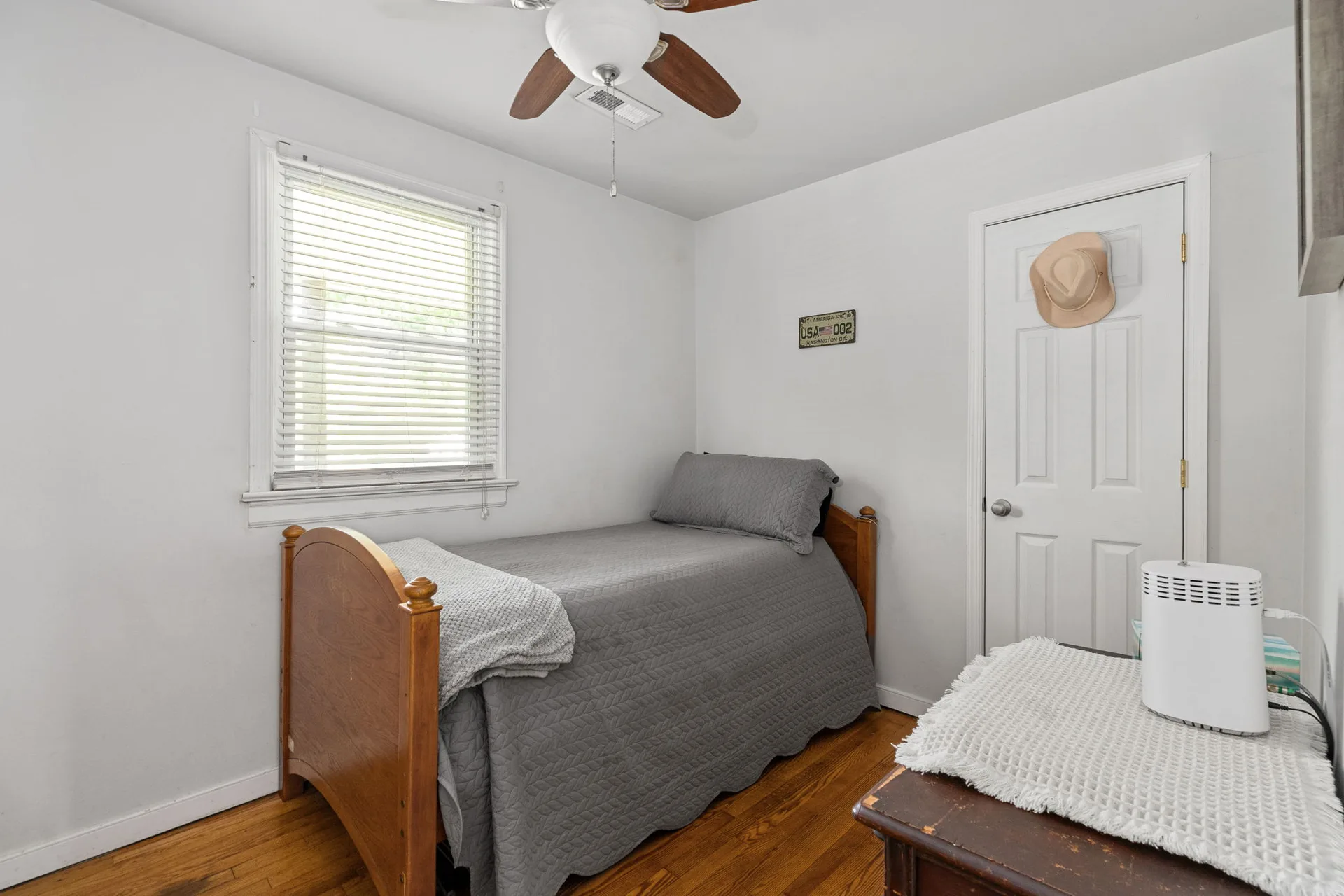 Small bedroom with refinished hardwood floors and white walls