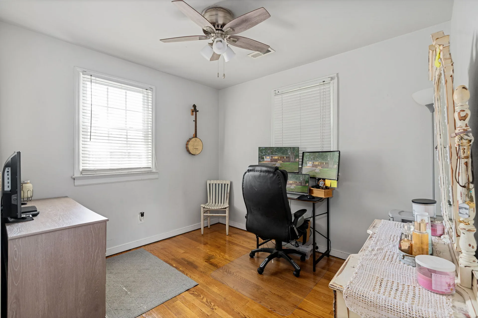 Bedroom home office with dual windows and hardwood floors