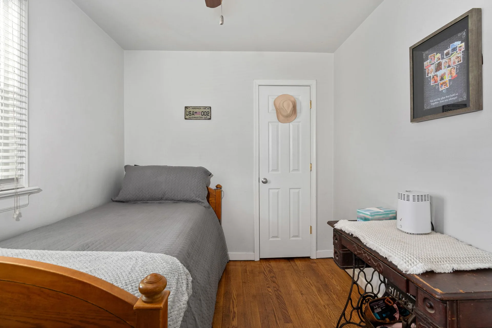 Secondary bedroom with hardwood flooring and white walls