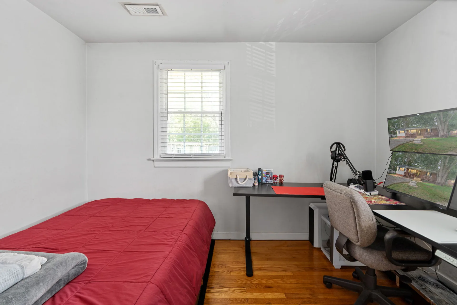 Secondary bedroom with red bedding and desk with dual monitors