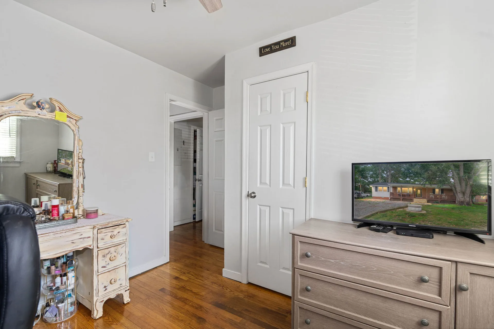 Bedroom with ornate vanity mirror and refinished hardwood