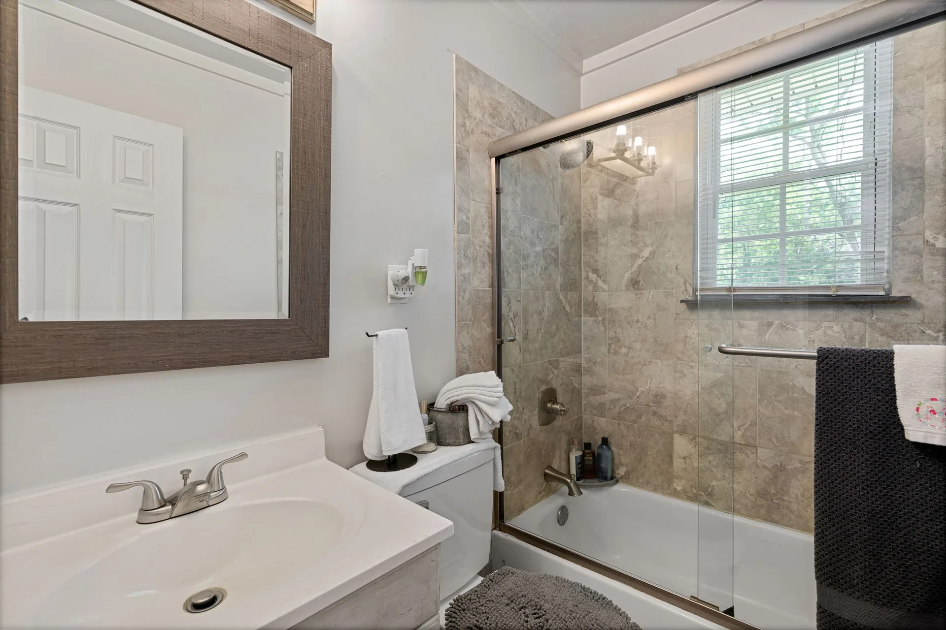 Bathroom with granite-look vanity and tiled shower surround
