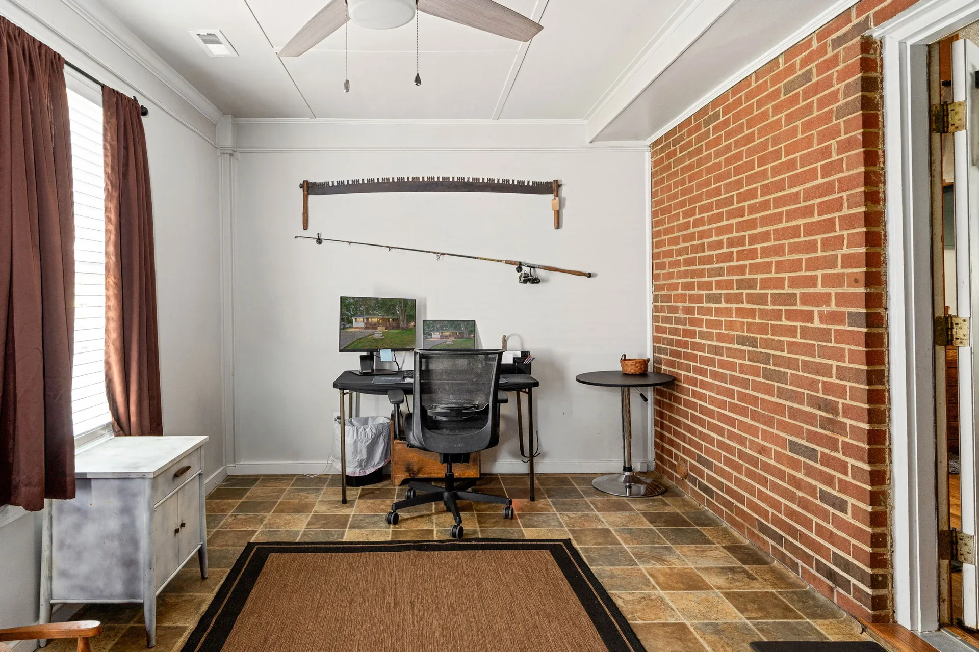 Den with exposed brick accent wall and ceramic tile flooring