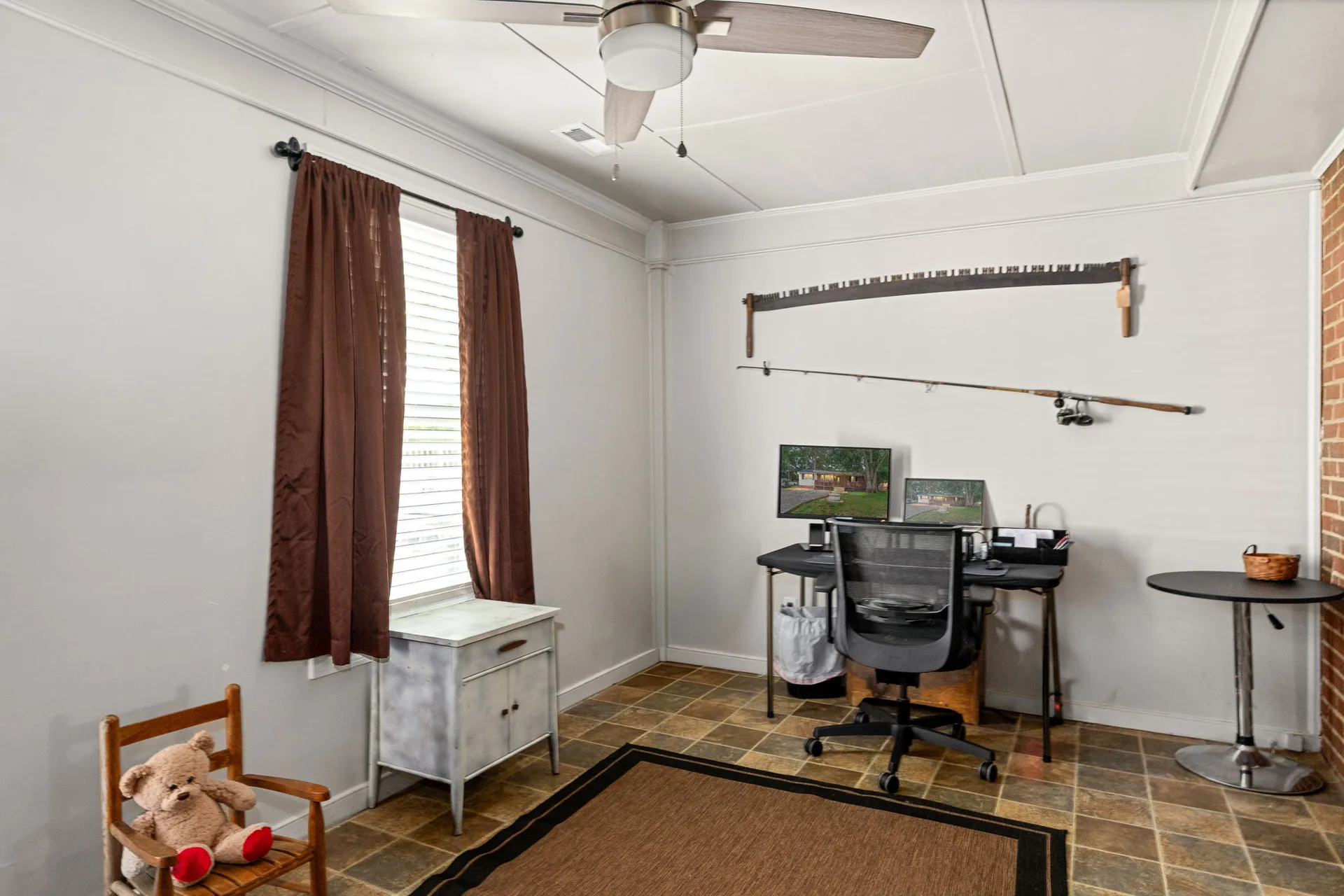 Bedroom office with brick accent wall and tile floor