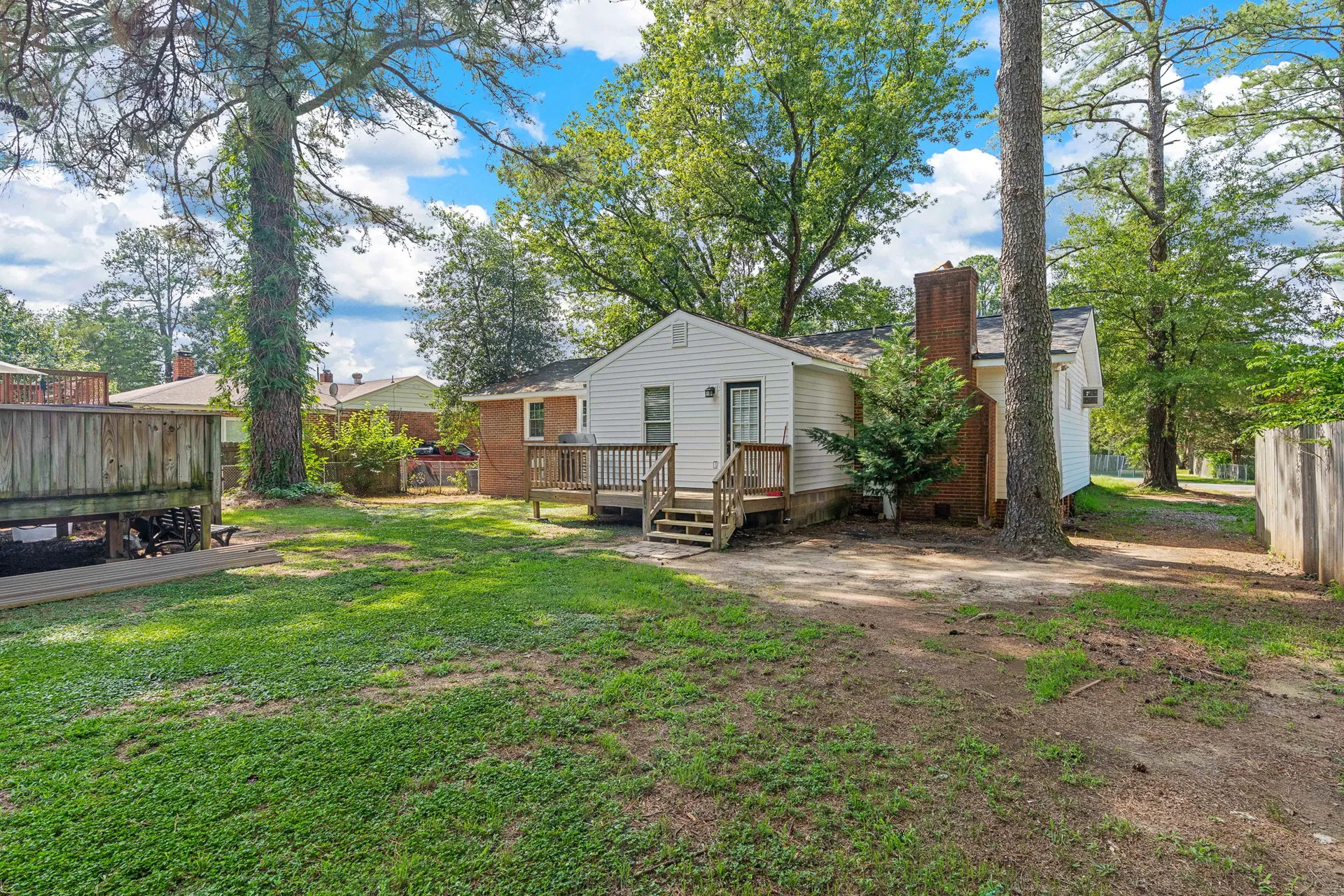 Rear of ranch home with large deck transitioning to fenced yard