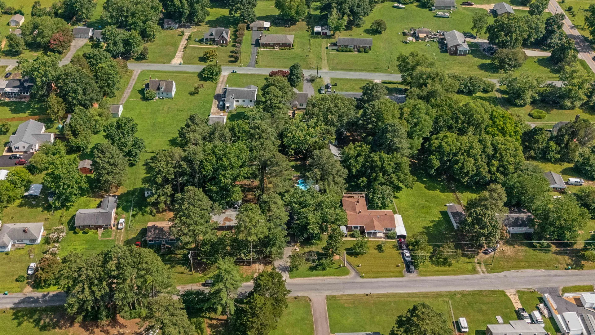 Drone aerial view of the property lot, pool, and surrounding neighborhood