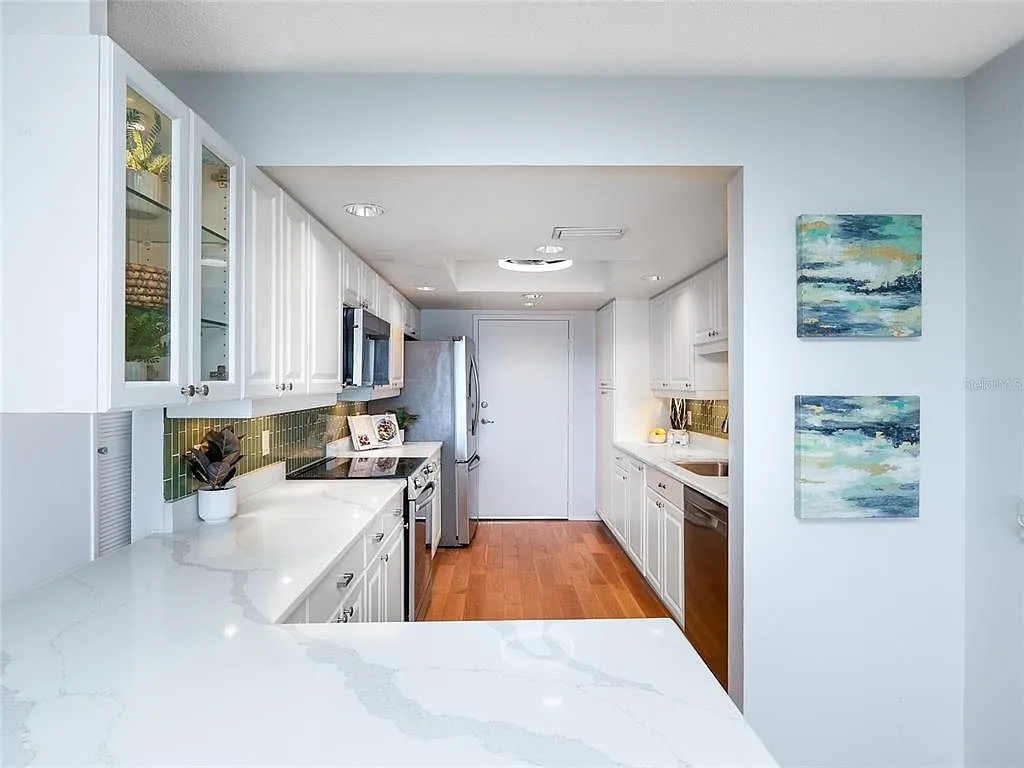 Renovated white kitchen with quartz countertops and green subway tile