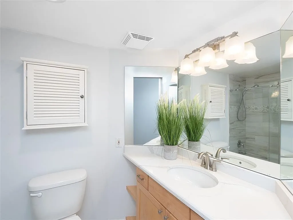 Bathroom with light wood vanity and grey stone-look tile shower