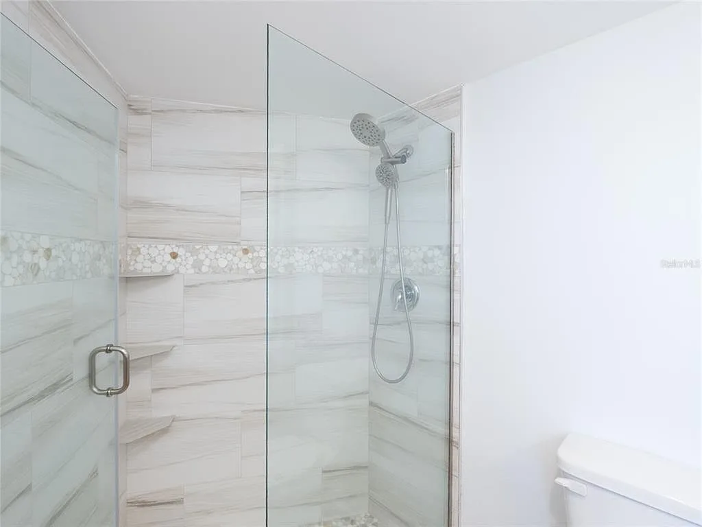 Walk-in shower with frameless glass and pebble accent