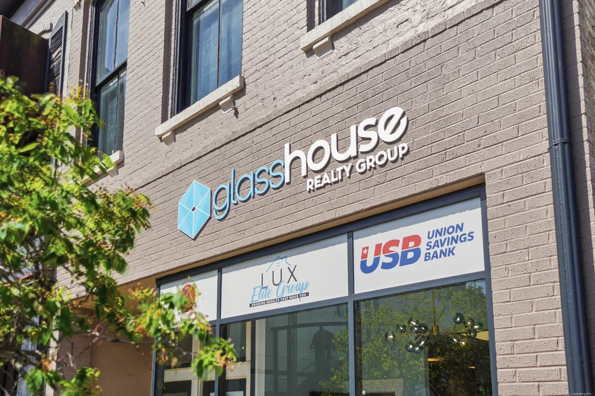 The Glasshouse Realty Group storefront in downtown Wilmington, Ohio — a brick building with large glass windows and professional signage