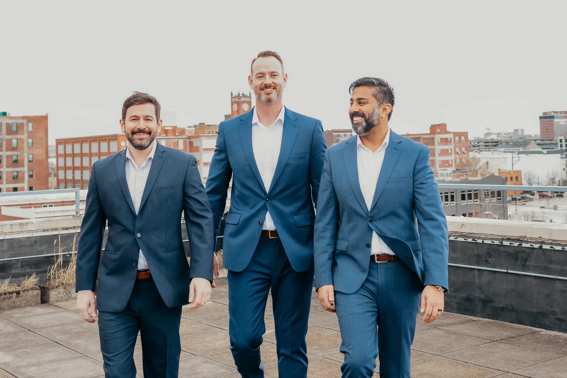 Glasshouse Realty team walking together on an urban rooftop with a city skyline in the background