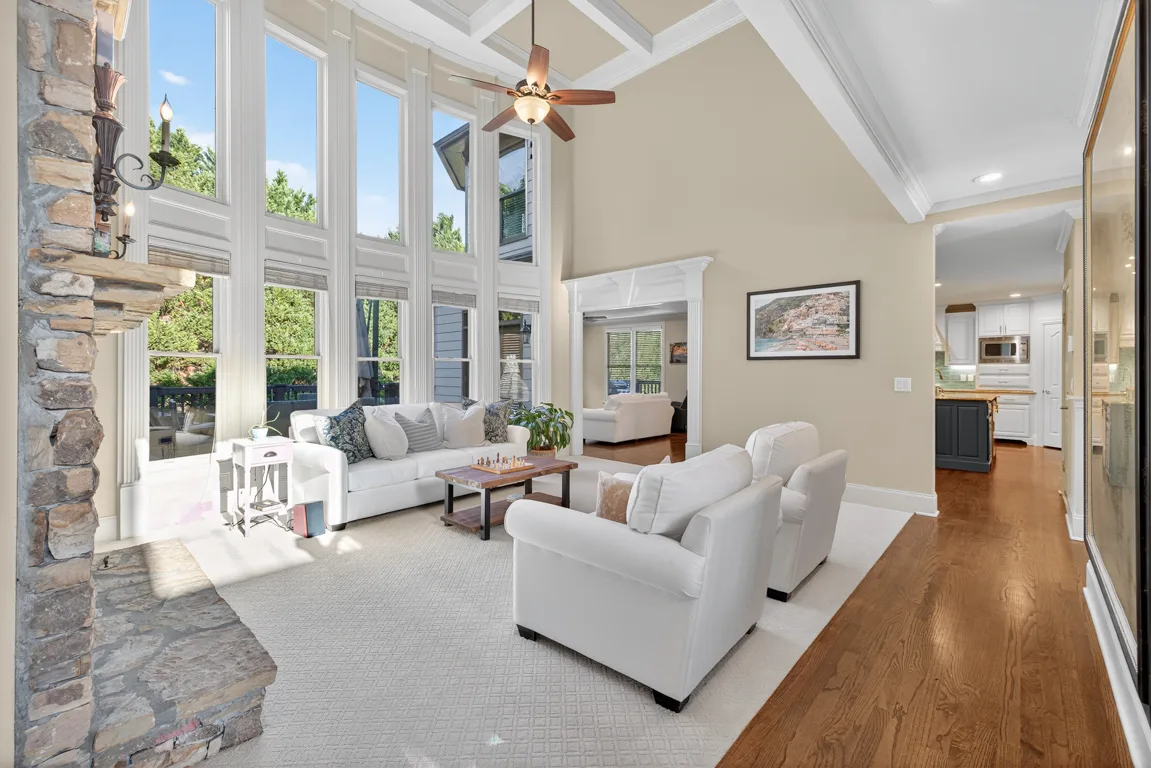 Two-story great room with floor-to-ceiling stacked stone fireplace, coffered ceiling, and tall windows at 909 Pathview Court