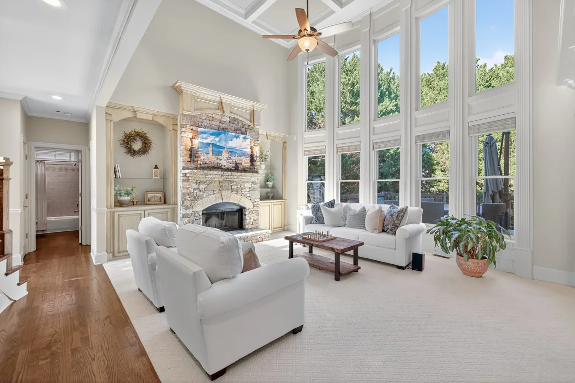 Living room with vaulted ceilings, stone fireplace, and coffered details