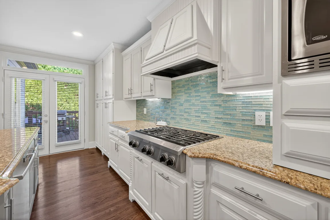 Kitchen cooking area with white cabinets and blue glass tile