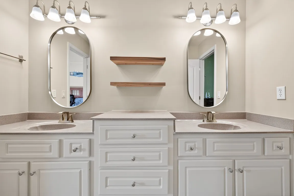 Secondary bathroom with double vanity and white cabinetry