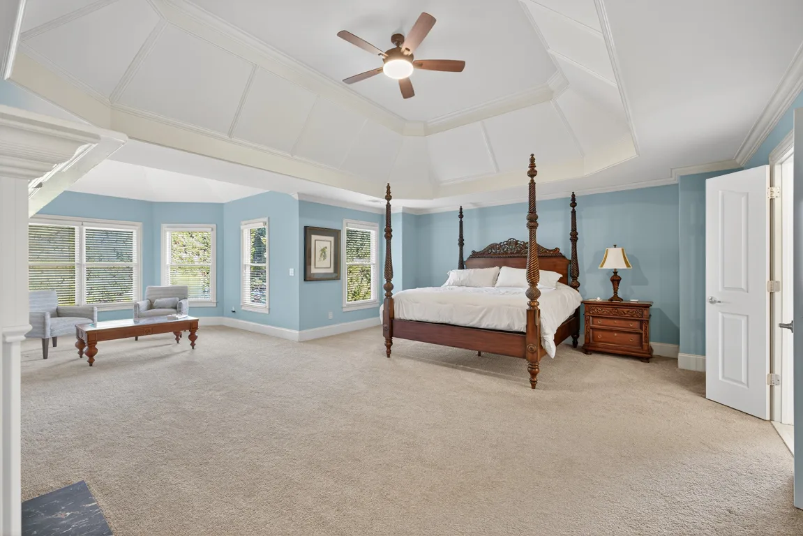 Master bedroom with tray ceiling, blue walls, and bay windows
