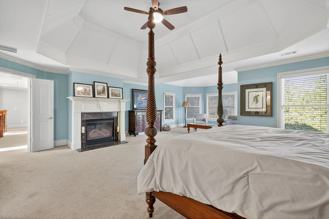 Master bedroom wide view with tray ceiling and stone fireplace