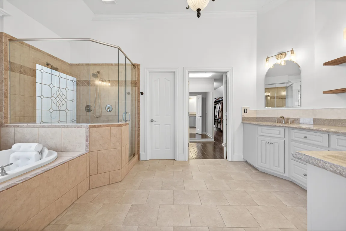 Master bathroom with dual vanity, stone countertops, and glass shower