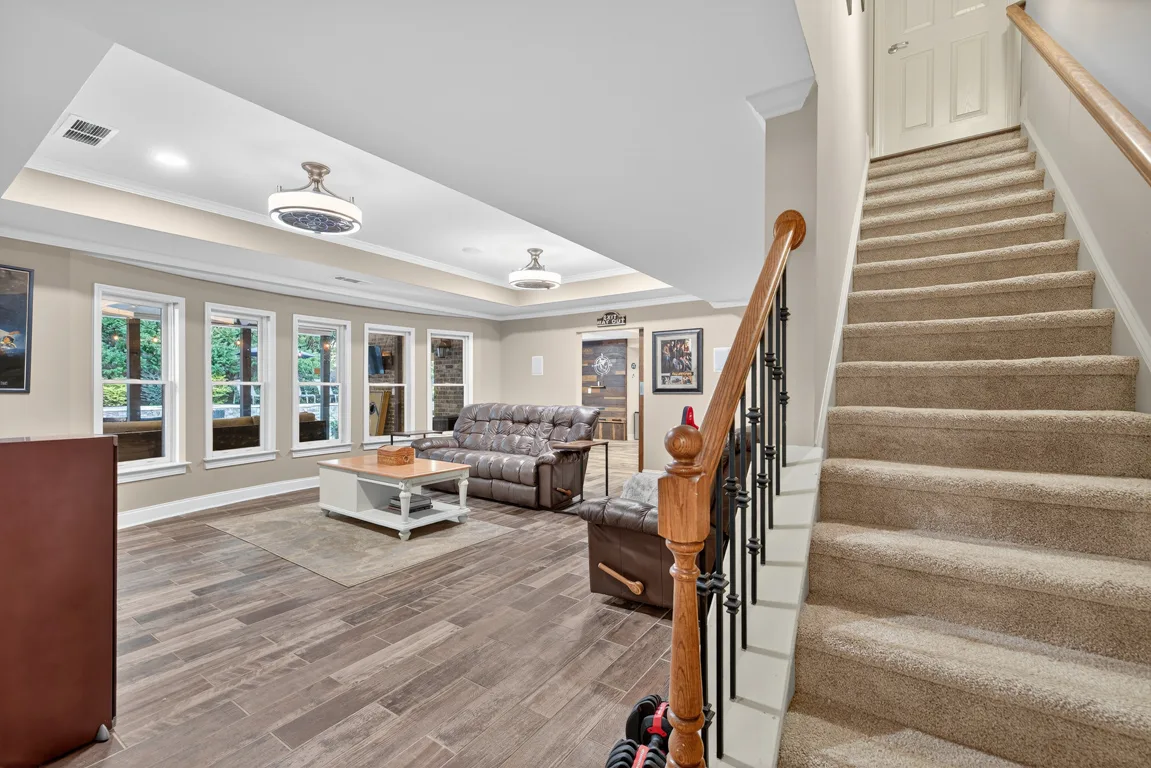 Living area with adjacent staircase and tray ceilings
