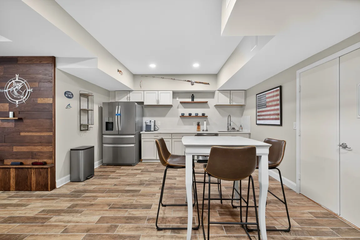Basement kitchenette with white shaker cabinets and wood accent wall