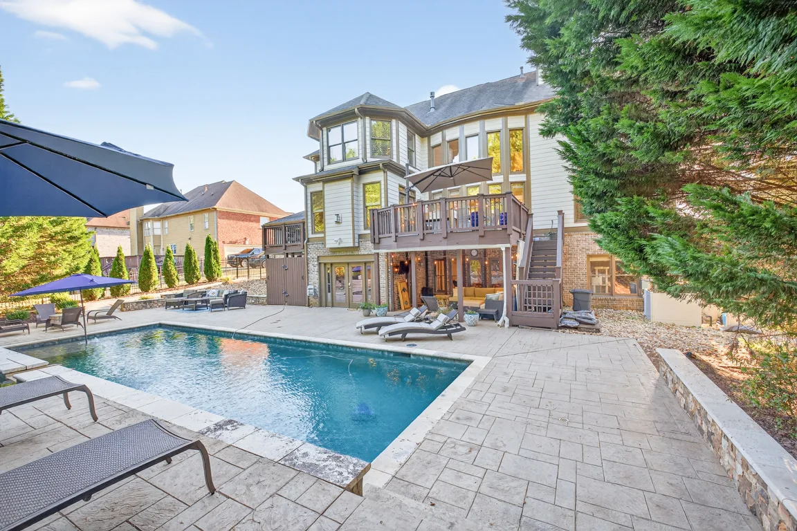 Backyard with pool, wooden deck, and stone accents
