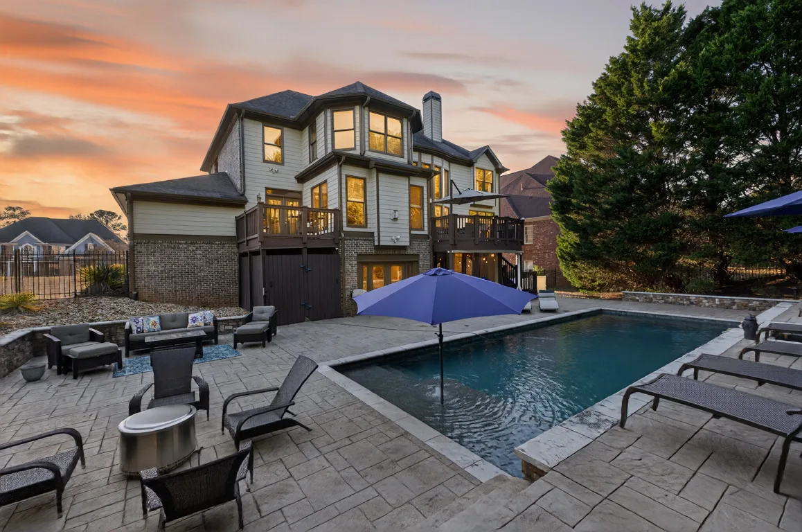 Backyard with resort-style saltwater pool, spa, multi-level deck, and stone-paver patio at golden hour at 909 Pathview Court