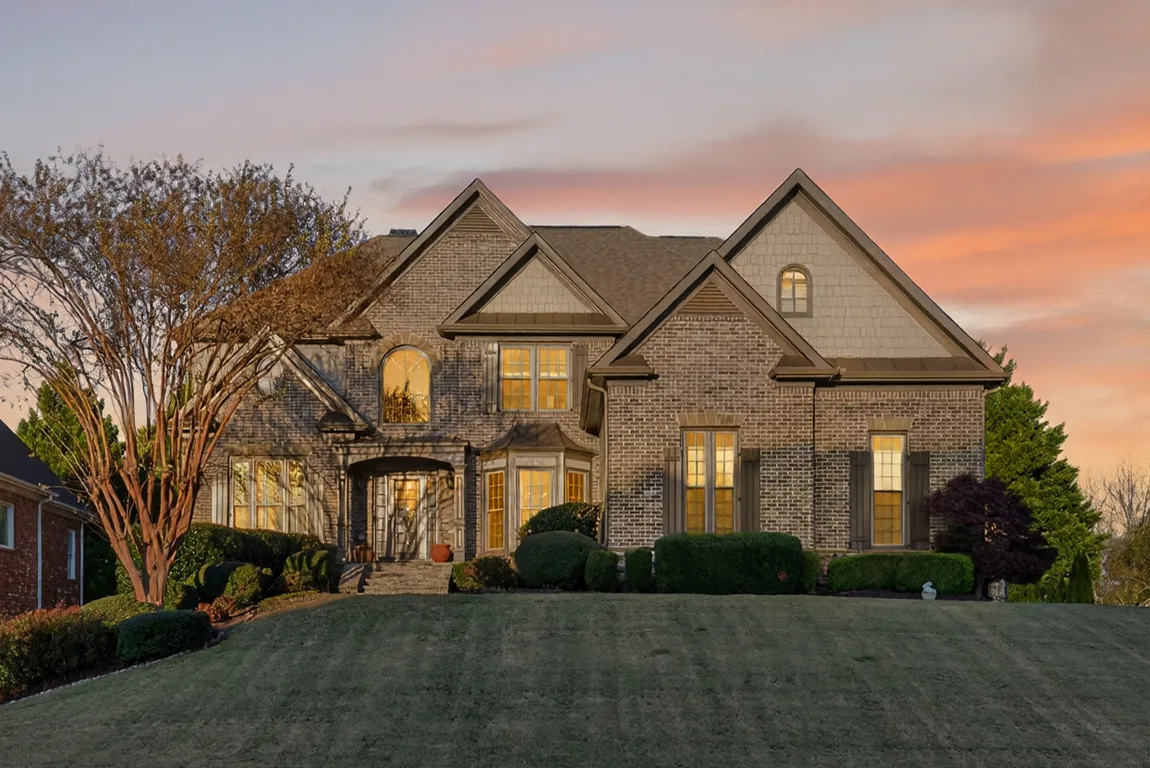 Front exterior of 909 Pathview Court, a custom luxury home in The Oaks at Apalachee Farms with warm sunset lighting and manicured landscaping