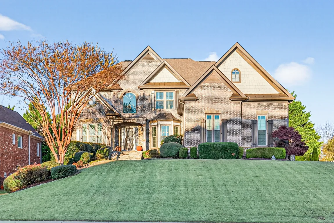 Front exterior with multi-tone tan brick, shake gables, and blue sky