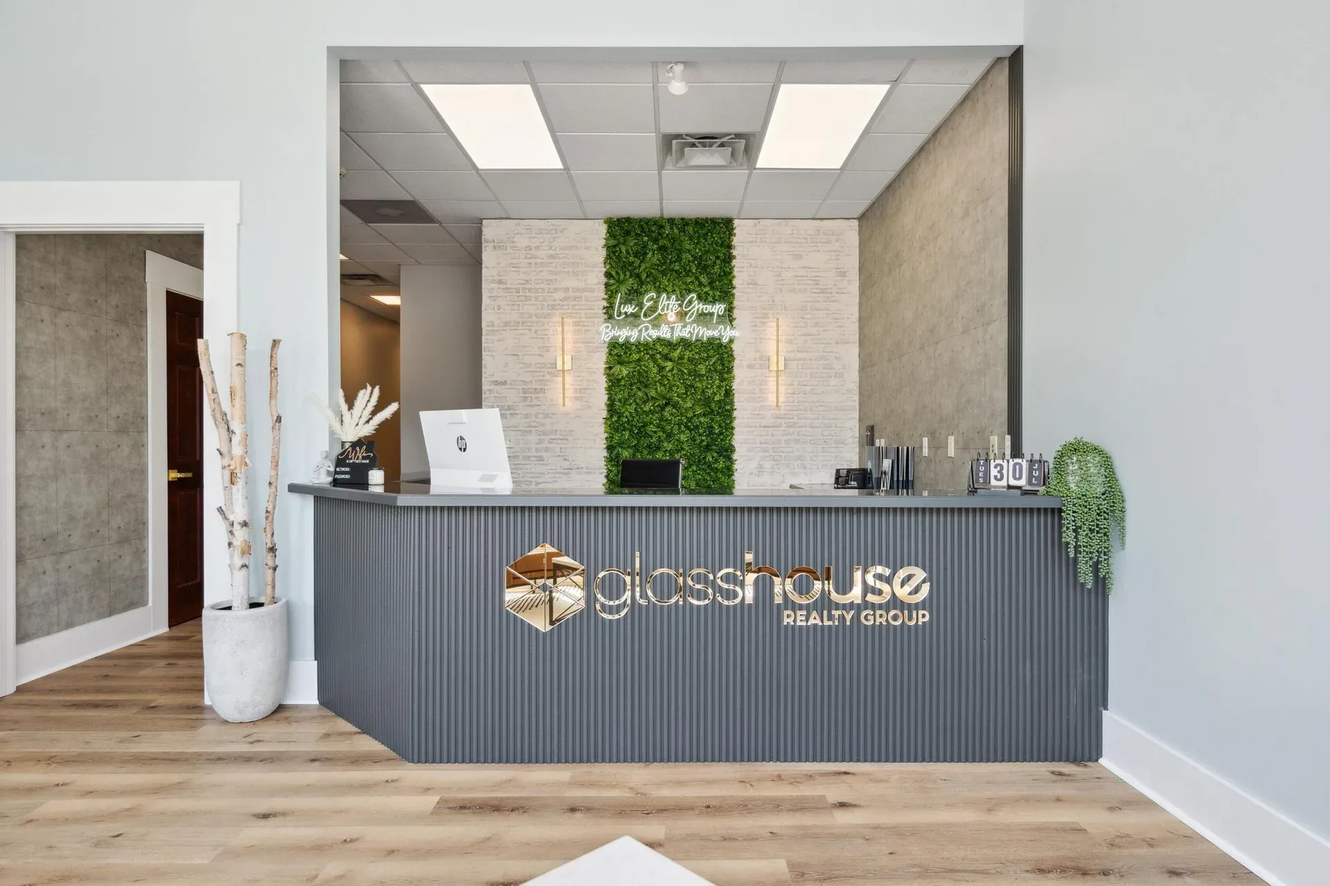 Modern office reception at Glasshouse Realty featuring a green moss accent wall and the Glasshouse Realty Group logo in Wilmington, Ohio