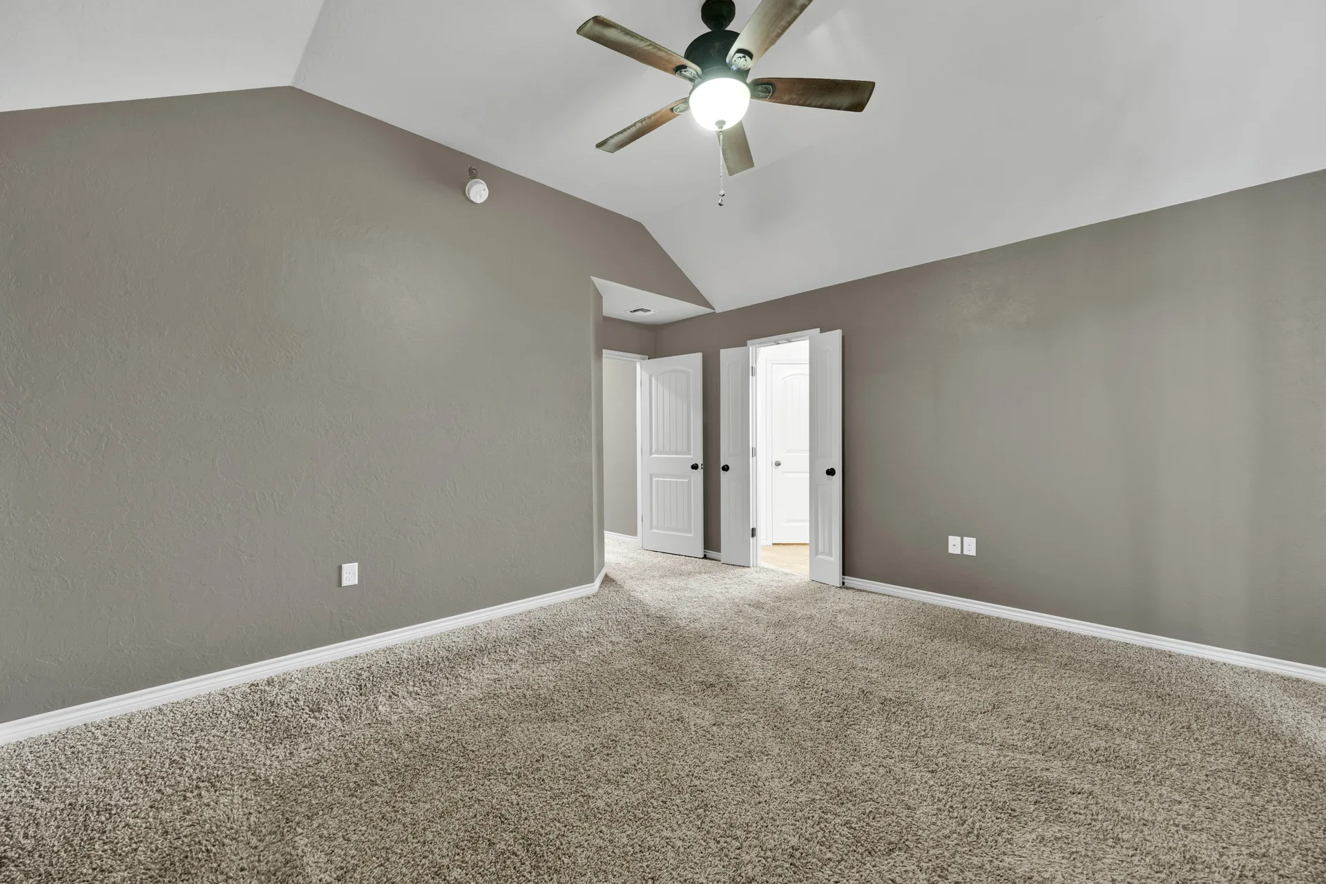 Primary bedroom with vaulted ceiling and neutral gray walls