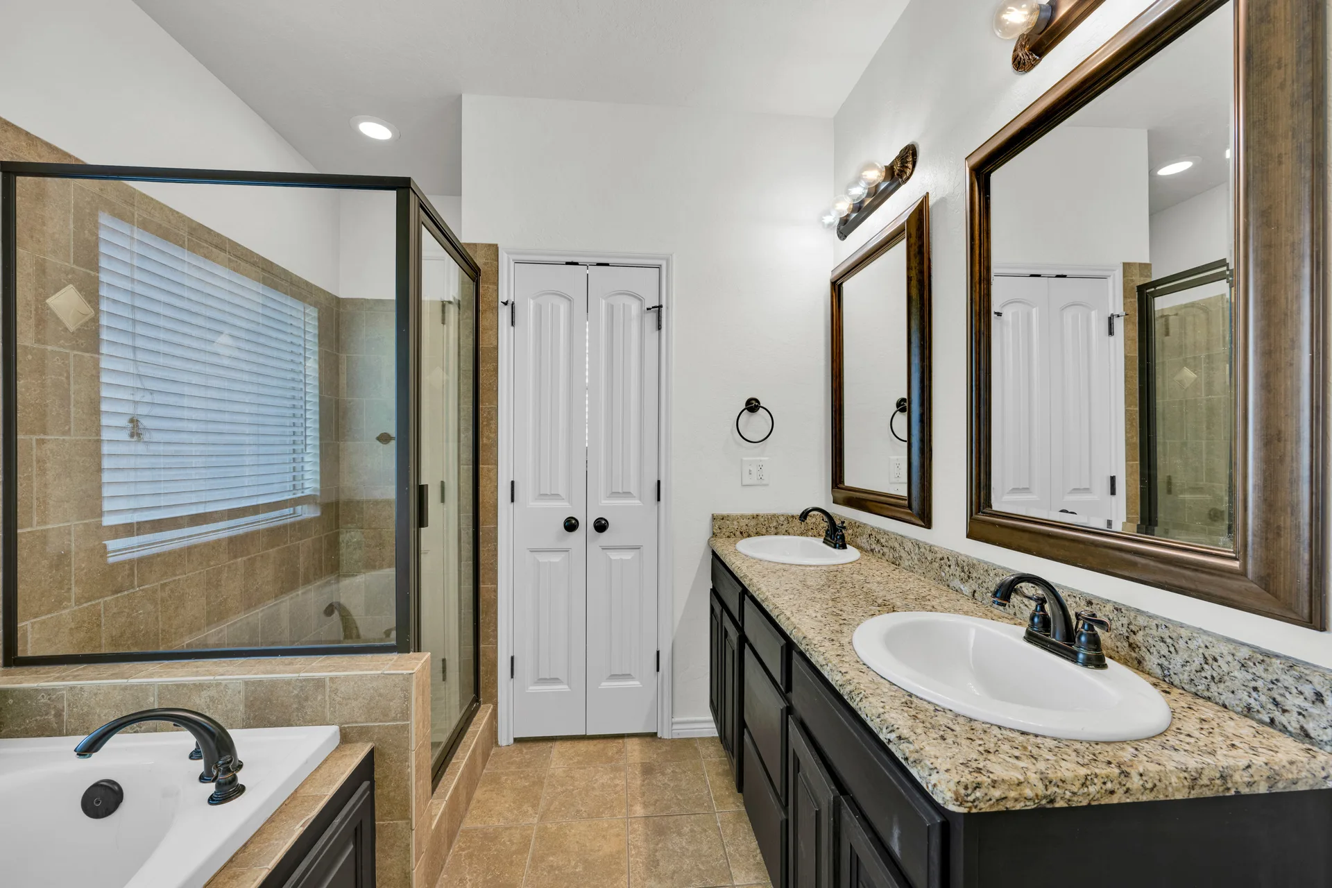 Primary bathroom vanity with dark cabinetry and tile surround