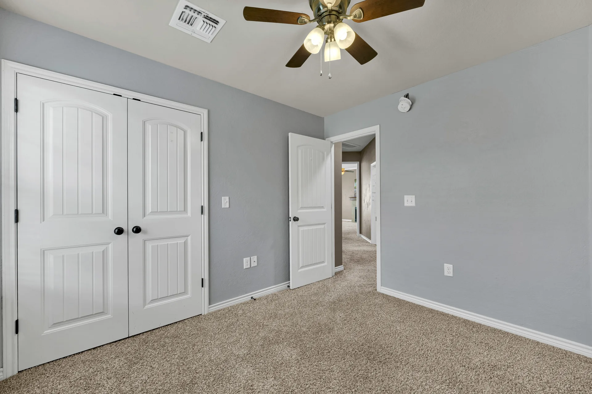 Empty bedroom looking toward closet and hallway