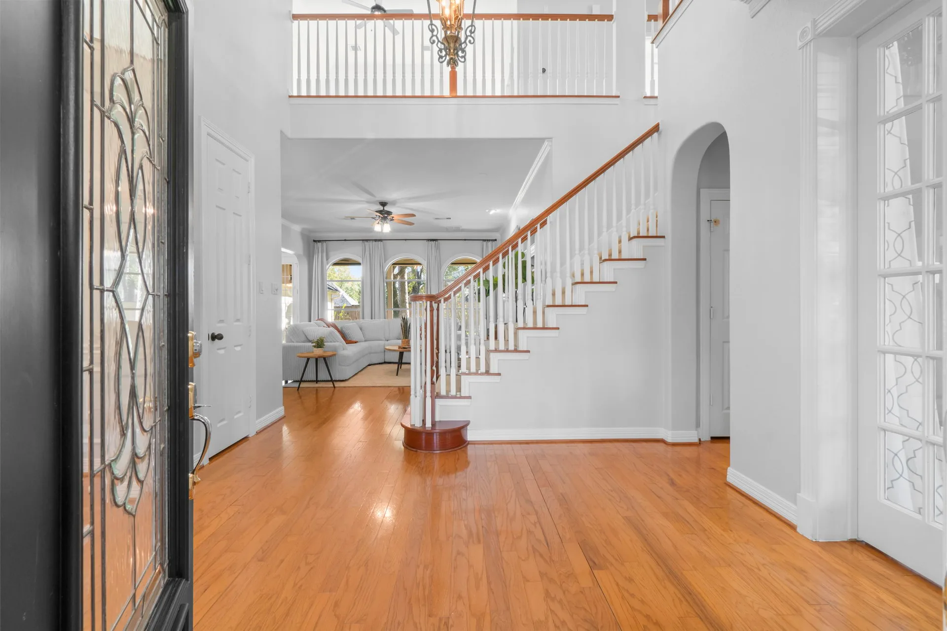 Wide-angle interior from front doorway looking into foyer and living room with curved staircase